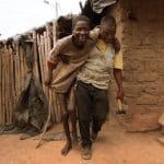 Grégoire Ahongbonon ayuda a caminar a un enfermo (Foto: Proyecto Grégoire)