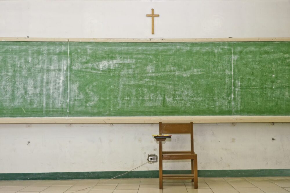 10855179 - empty school blackboard in classroom with crucifix and chair